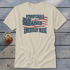 Cream t-shirt featuring a distressed American flag graphic and text reading Pennsylvania Raised American Made.