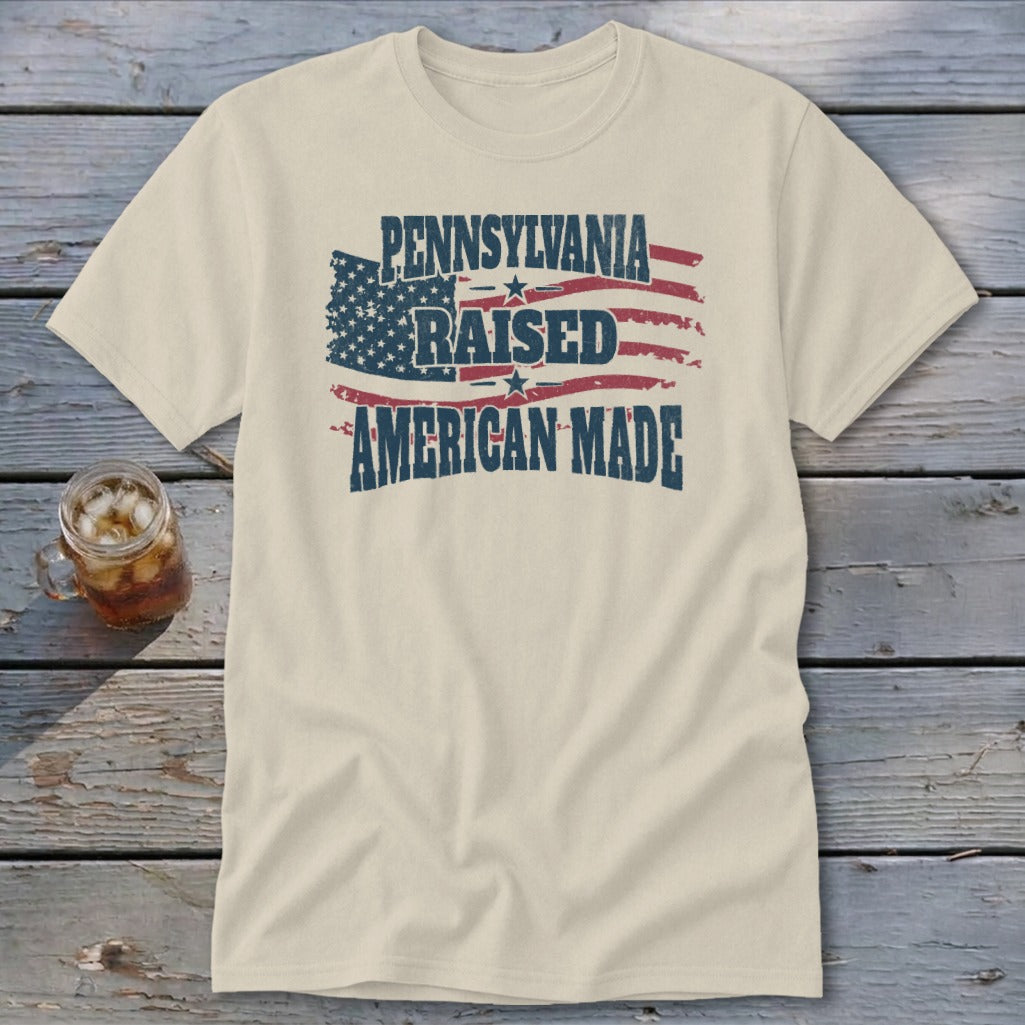 Cream t-shirt featuring a distressed American flag graphic and text reading Pennsylvania Raised American Made.