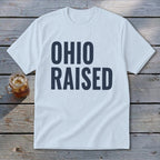 Light blue t-shirt with dark blue text reading "OHIO RAISED".
