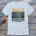 White t-shirt with graphic of sunrise over mountains and text "RIDGELINE AT DAYBREAK".