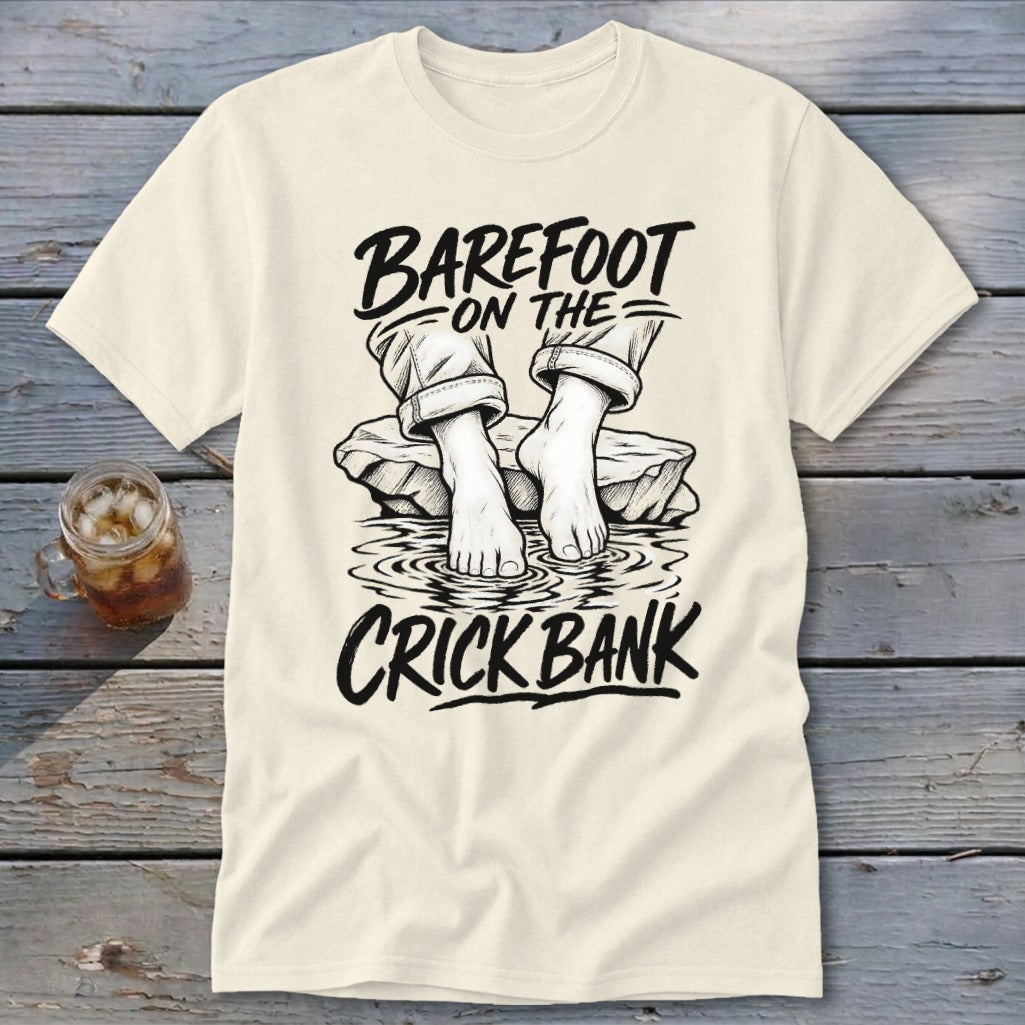 Cream t-shirt with text "BAREFOOT ON THE CRICK BANK" and illustration of bare feet in water.