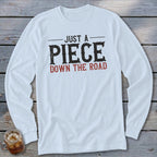 White long-sleeve shirt with "JUST A PIECE DOWN THE ROAD" text.