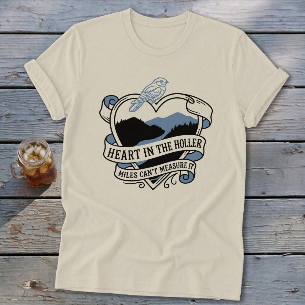 Cream t-shirt with a heart graphic featuring mountains, a bird, and text.