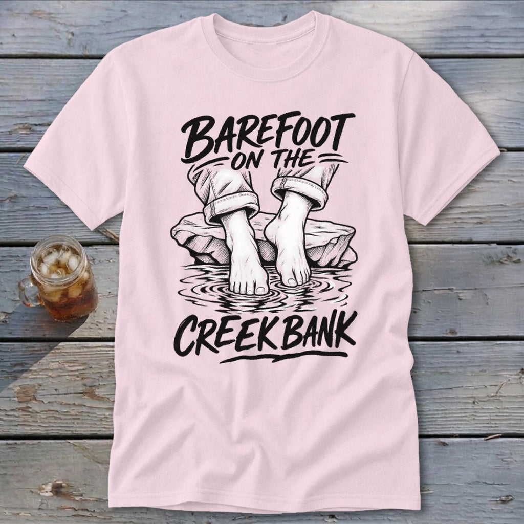 Pink t-shirt with black graphic of bare feet in water and text "Barefoot On The Creek Bank".