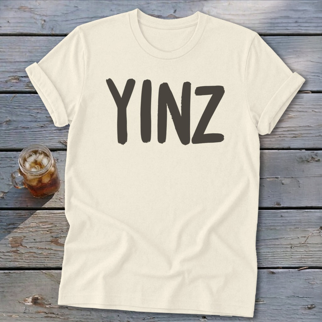 Cream t-shirt with bold, dark gray "YINZ" text.