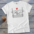 White t-shirt with line art of couple and dog on swing overlooking mountains with red heart.
