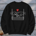 Black sweatshirt with white line art of couple and dog on a swing under a red heart.