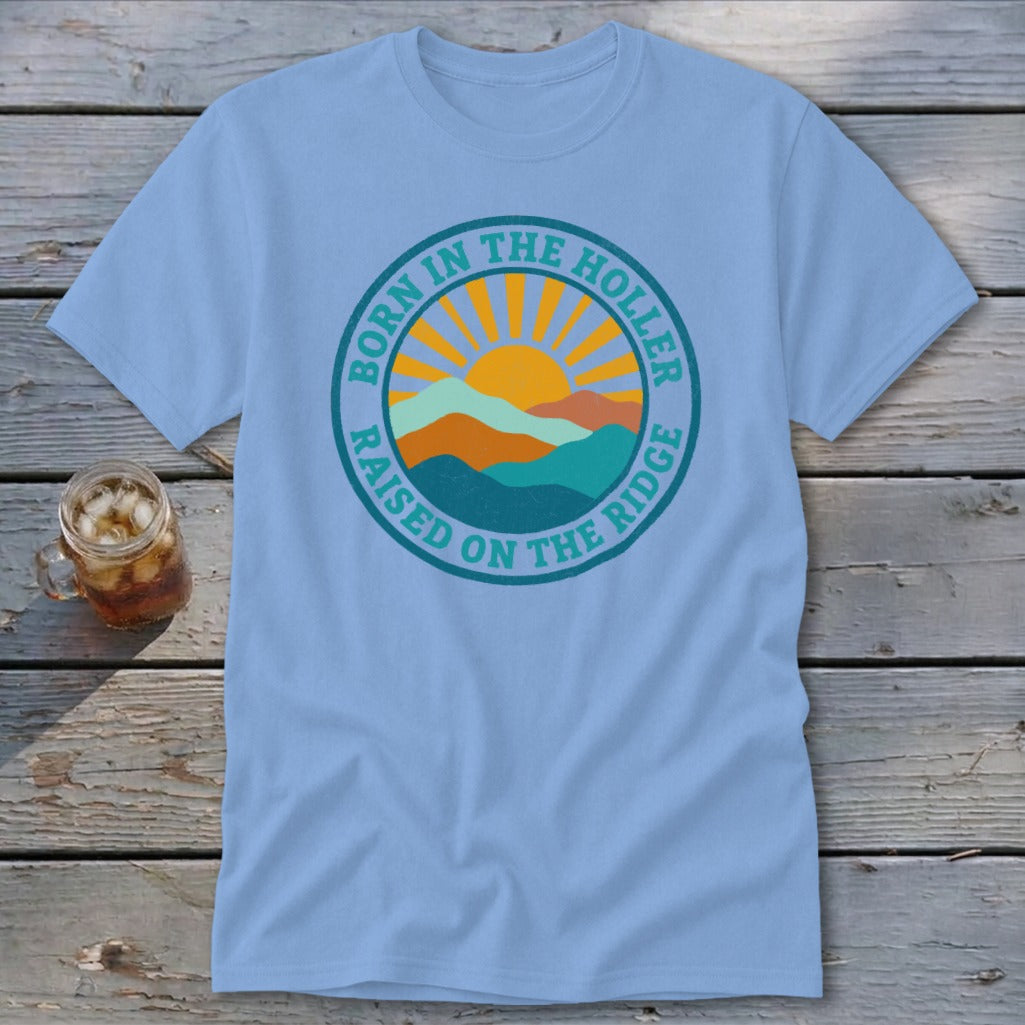 Light blue t-shirt featuring a circular retro mountain graphic and the text Born in the Holler, Raised on the Ridge.