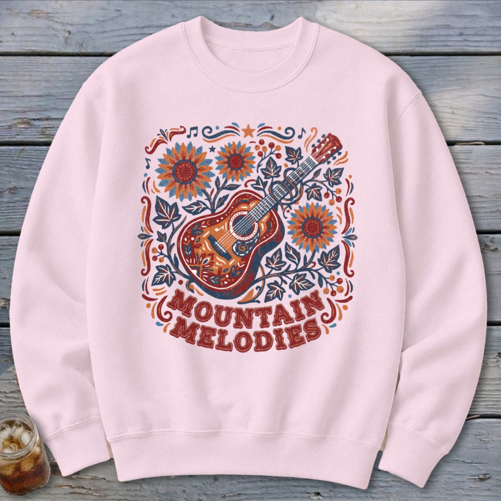 Light pink crewneck sweatshirt featuring a colorful graphic of a guitar, sunflowers, and the text Mountain Melodies.