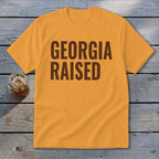 Orange t-shirt with "GEORGIA RAISED" text in dark brown font.