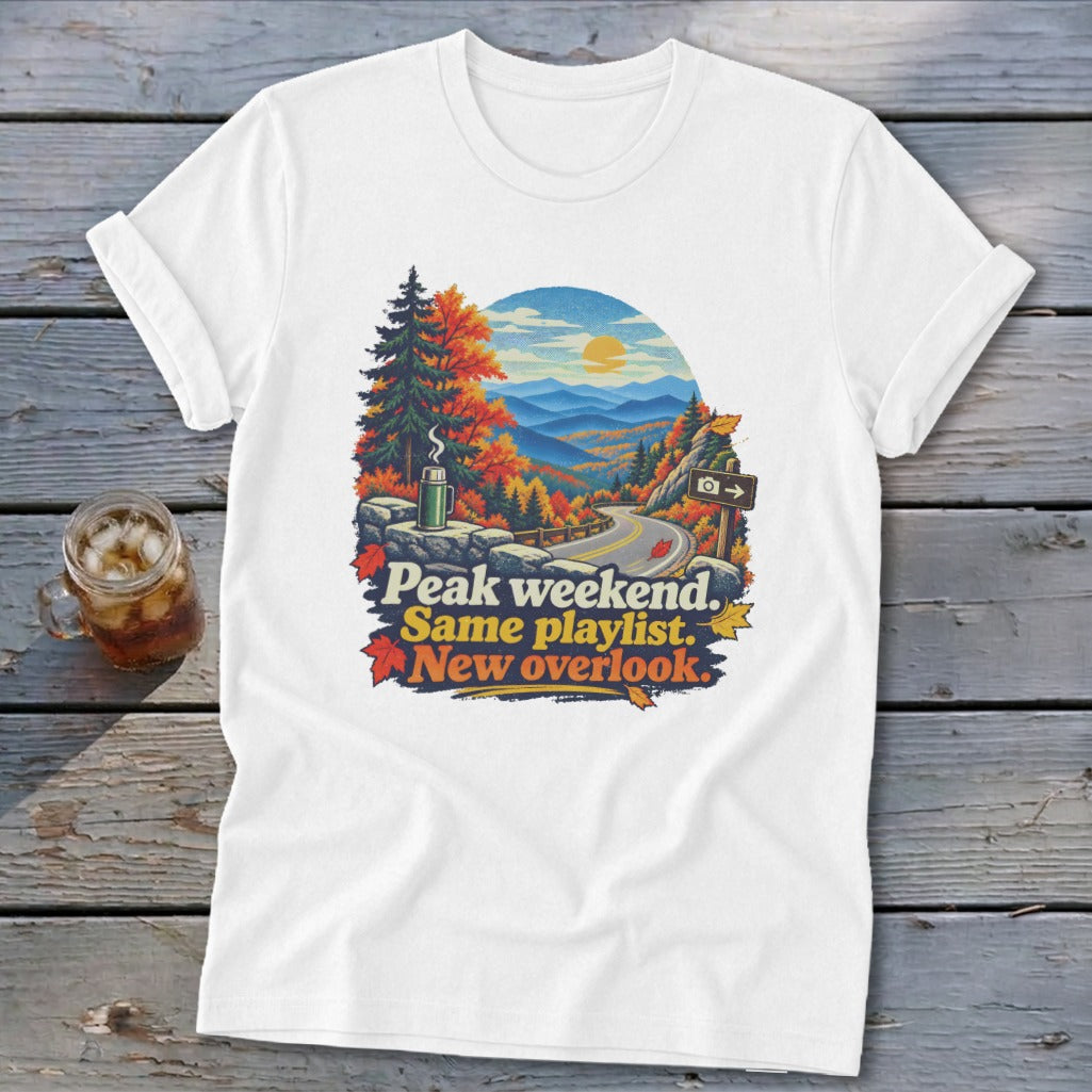 White t-shirt with scenic mountain overlook graphic and text "Peak weekend. Same playlist. New overlook."