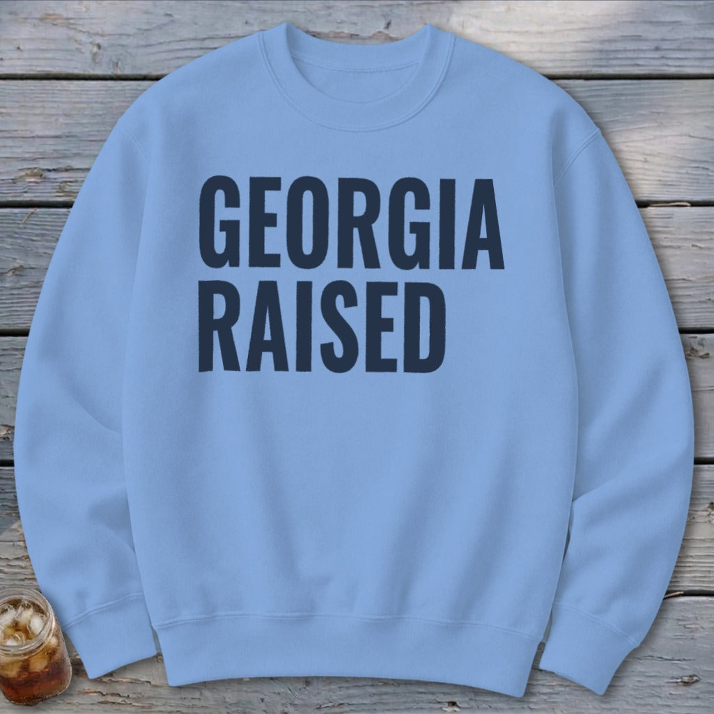 Light blue crewneck sweatshirt with navy blue text "GEORGIA RAISED"