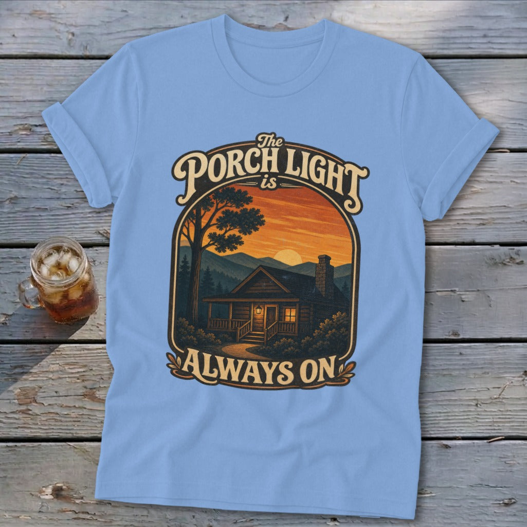 Light blue t-shirt with graphic "The Porch Light Is Always On" and a cabin scene.
