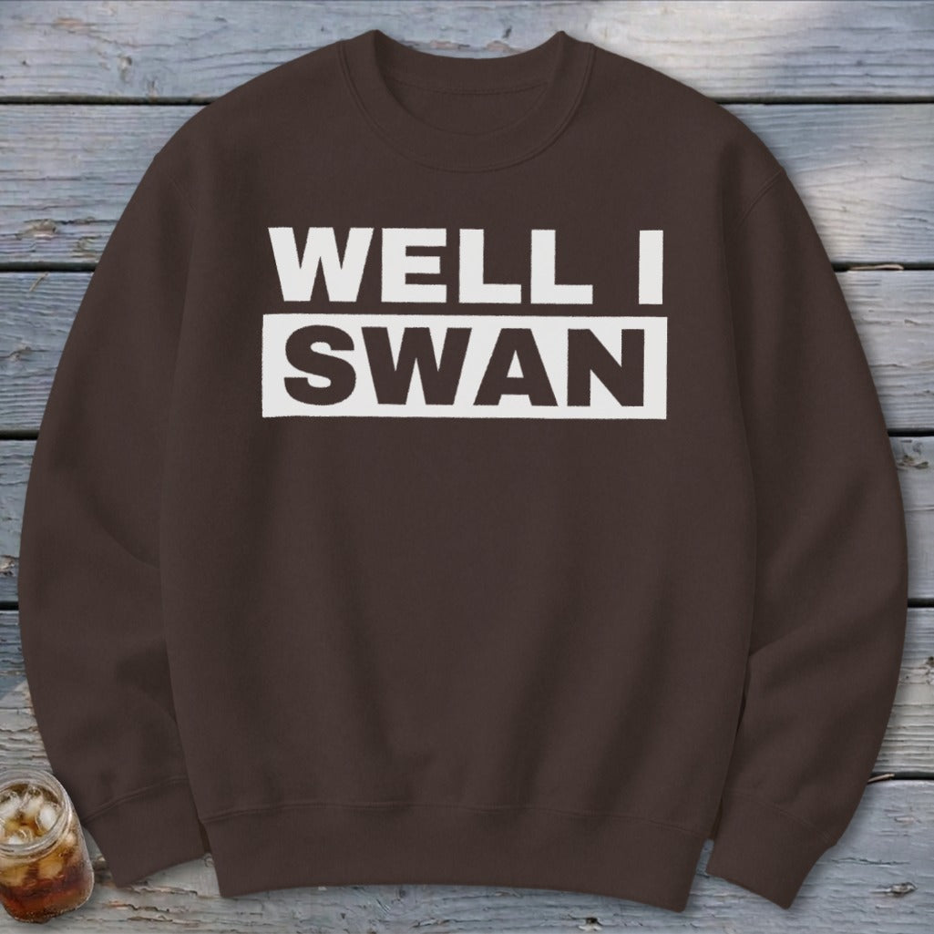 Brown crewneck sweatshirt printed with the text "WELL I SWAN" in a white box on the chest.