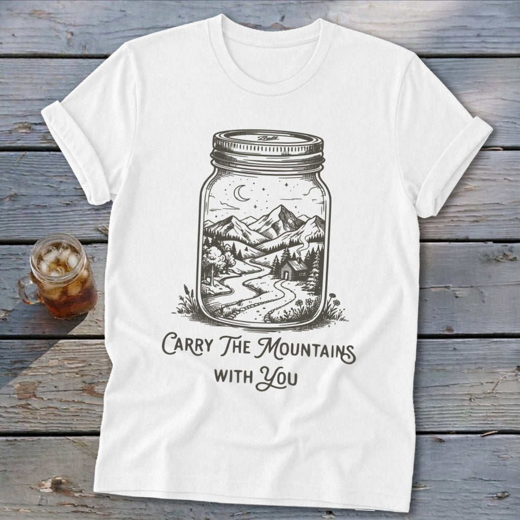 A white t-shirt featuring a mason jar graphic containing a mountain landscape and the text Carry The Mountains With You.