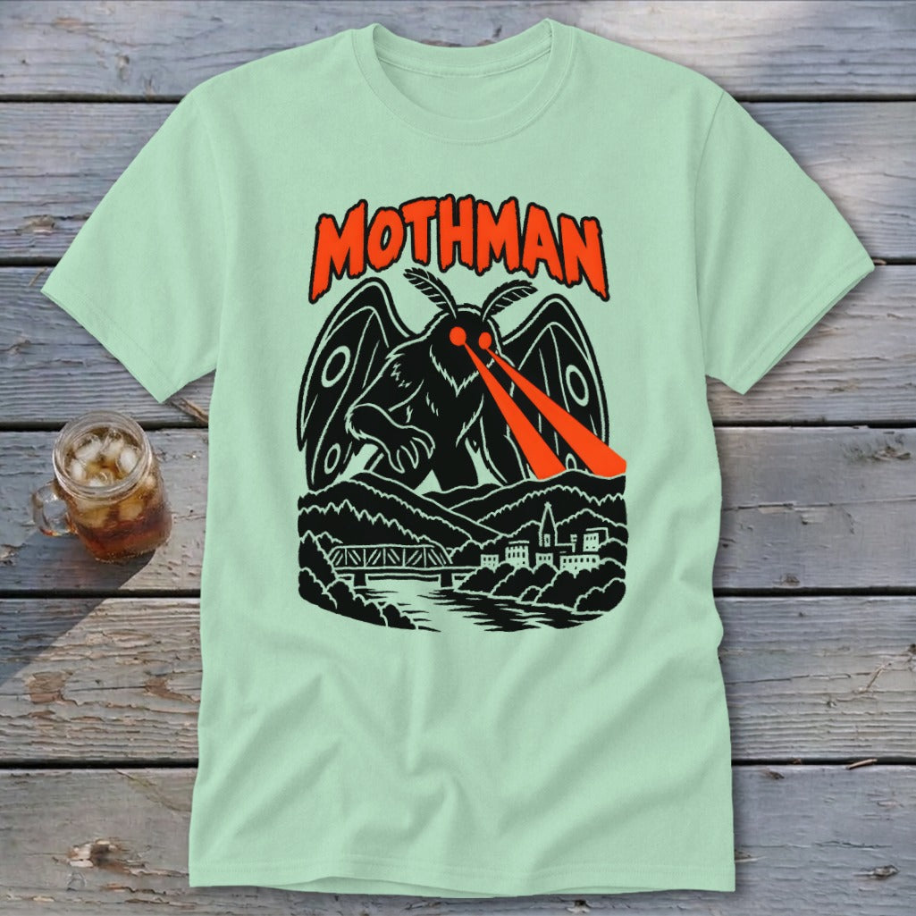 Light green t-shirt featuring a black mothman with red laser eyes over a town and bridge.