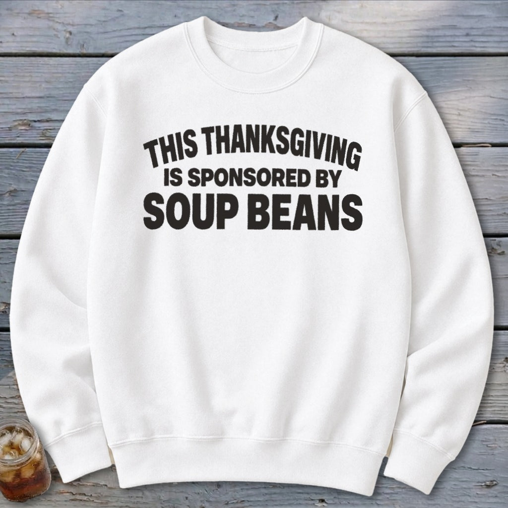 A white crewneck sweatshirt featuring black text that reads THIS THANKSGIVING IS SPONSORED BY SOUP BEANS.