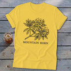 Yellow t-shirt with black rhododendron graphic and "MOUNTAIN BORN" text.