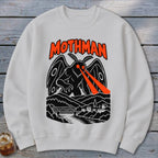 Mothman graphic with orange text and red laser eyes over a town and bridge.