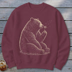 Maroon sweatshirt with a graphic of a bear blowing dandelion seeds.