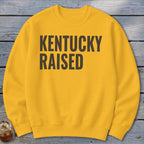 Yellow sweatshirt with "KENTUCKY RAISED" text in bold, dark gray letters.