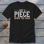Black t-shirt with "JUST A PIECE DOWN THE ROAD" text.