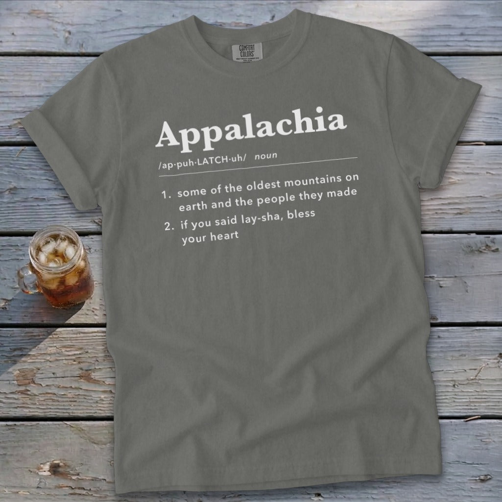 A grey crewneck t-shirt featuring dictionary-style text defining Appalachia lies flat on weathered wooden boards.