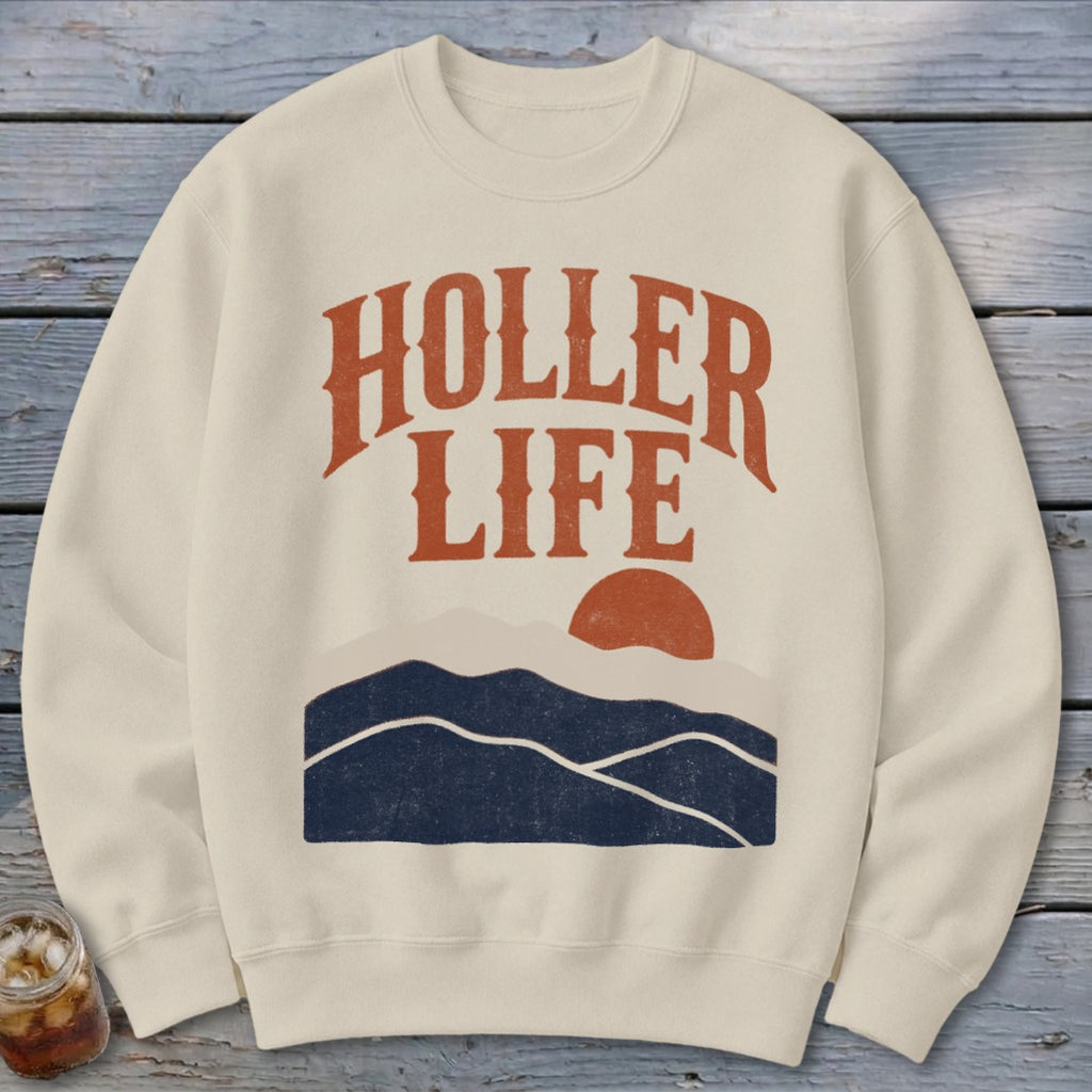 Beige crewneck sweatshirt featuring the text HOLLER LIFE above a sunset mountain landscape.