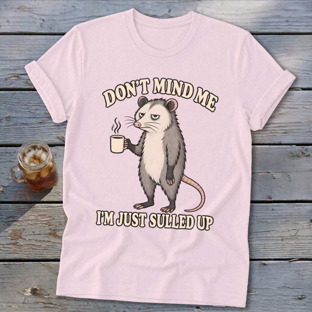 Pink t-shirt with opossum holding coffee and text "DON'T MIND ME I'M JUST SULLED UP".