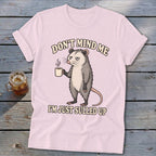 Pink t-shirt with opossum holding coffee and text "DON'T MIND ME I'M JUST SULLED UP".