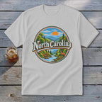 White t-shirt with a circular graphic of North Carolina mountains, river, deer, and sun.