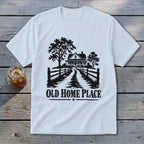 White t-shirt with a black graphic of a farmhouse, trees, fence, and text "OLD HOME PLACE".
