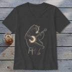 Black bear playing banjo while sitting on a stool, on a dark t-shirt.