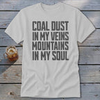 A light gray crewneck t-shirt features black text that reads COAL DUST IN MY VEINS MOUNTAINS IN MY SOUL.