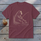 Burgundy t-shirt with a sketch of a bear fishing on a riverbank.
