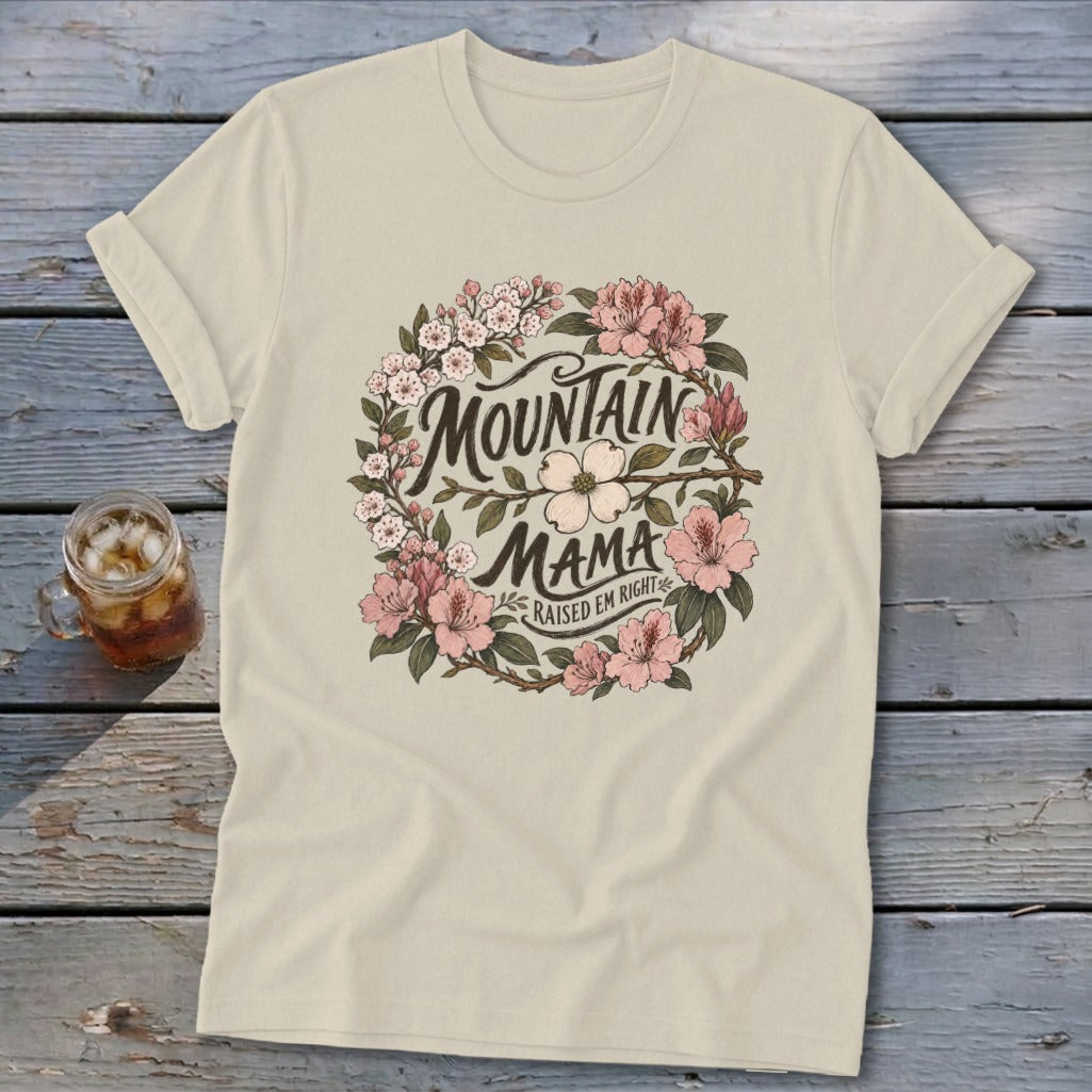 Cream t-shirt with "Mountain Mama Raised Em Right" floral wreath graphic.