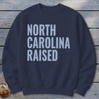 Navy sweatshirt with "NORTH CAROLINA RAISED" text in light blue.
