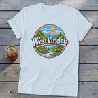 White t-shirt with a circular graphic featuring mountains, a river, trees, a deer, and "West Virginia" text.