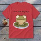 A red t-shirt displays an illustration of a green frog on a lily pad with text reading finer than frog's hair.