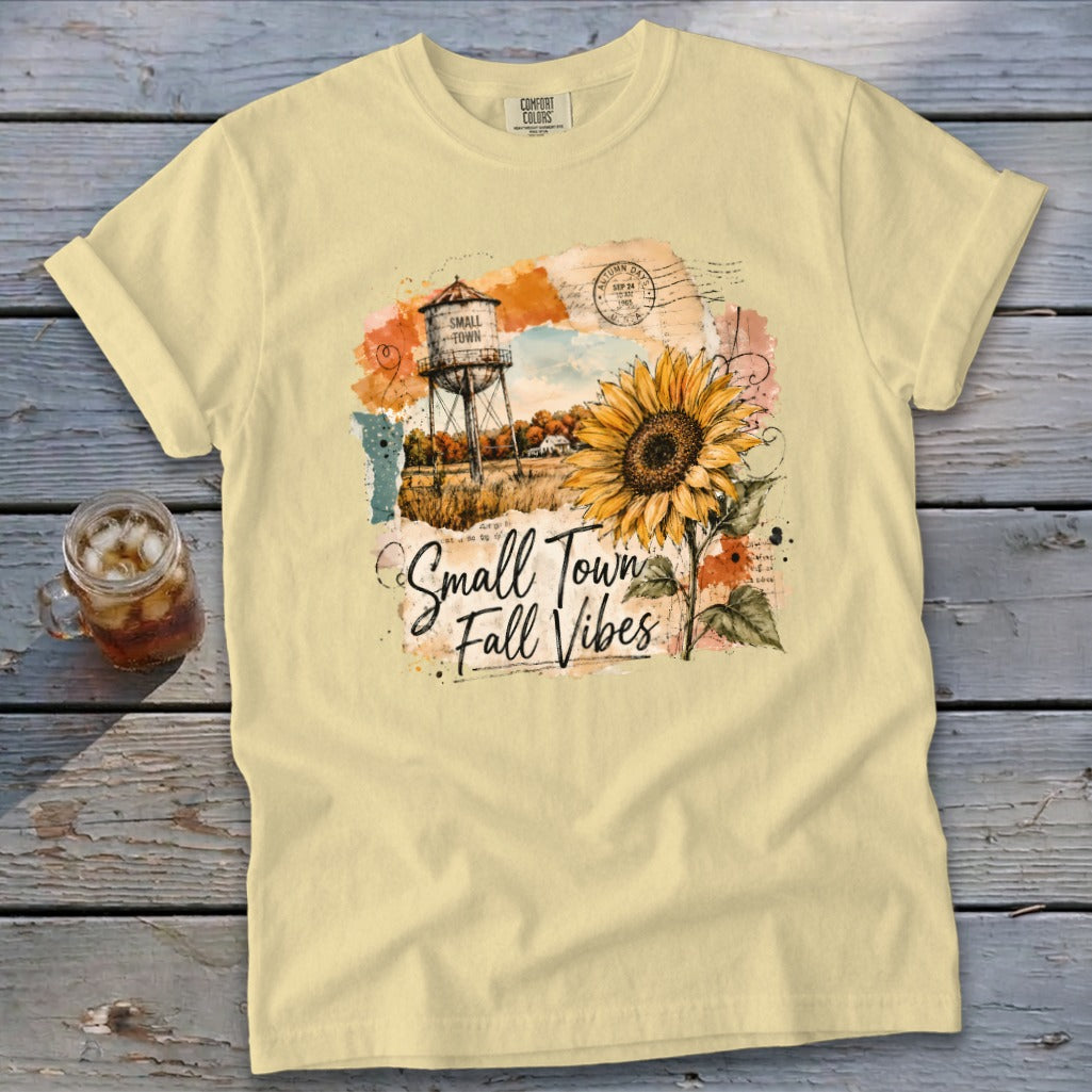 Yellow t-shirt with a graphic of a water tower, sunflower, and text "Small Town Fall Vibes."