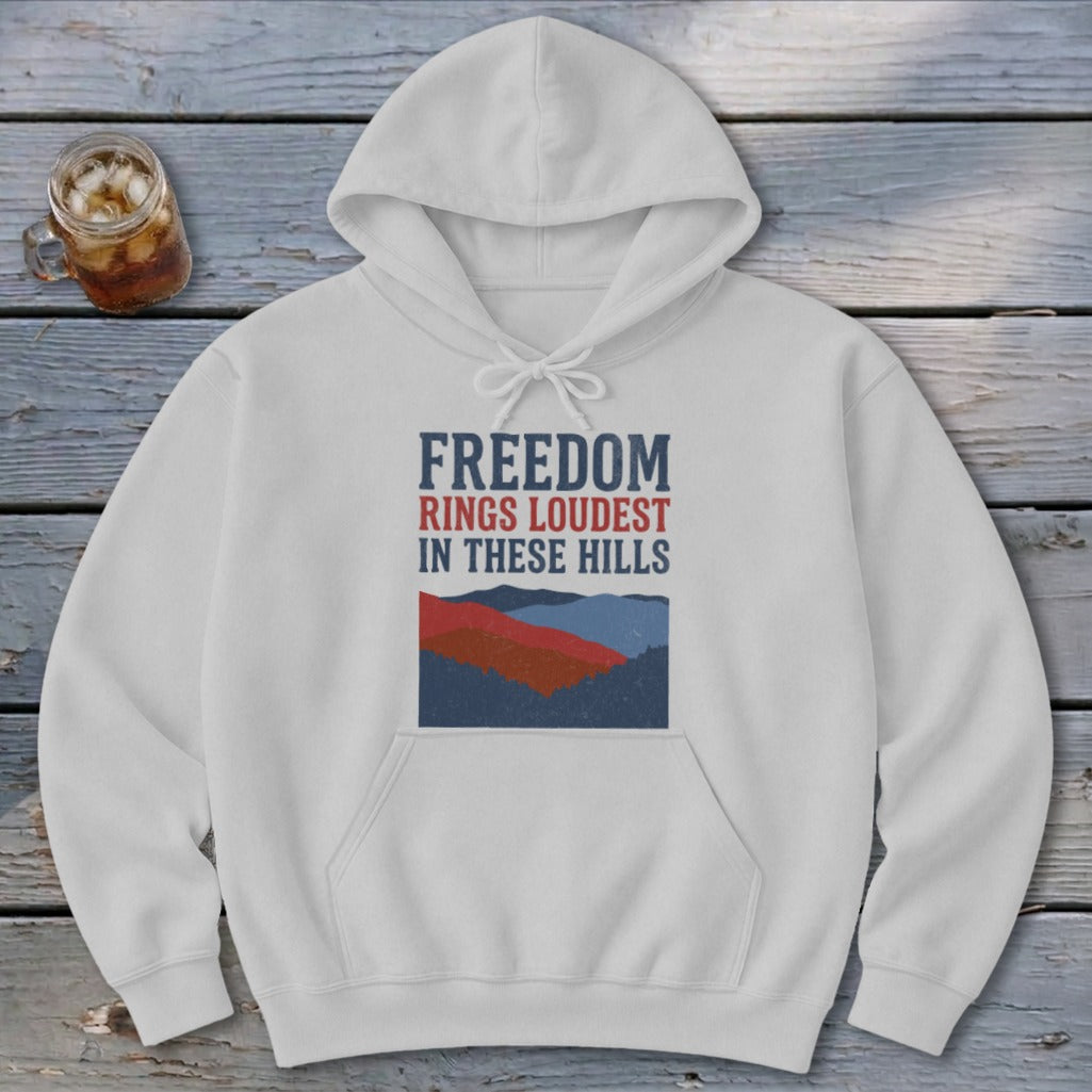 A light gray hoodie featuring blue and red mountain graphics and text that reads Freedom Rings Loudest In These Hills.