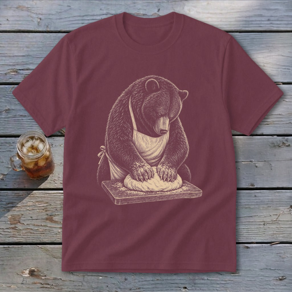 Bear wearing apron kneading dough on a cutting board, illustrated graphic on a maroon t-shirt.