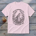 A light pink crewneck t-shirt featuring a vintage botanical illustration of a whippoorwill and cornstalks, with the text When The Whippoorwill Calls It's Time To Plant Corn.