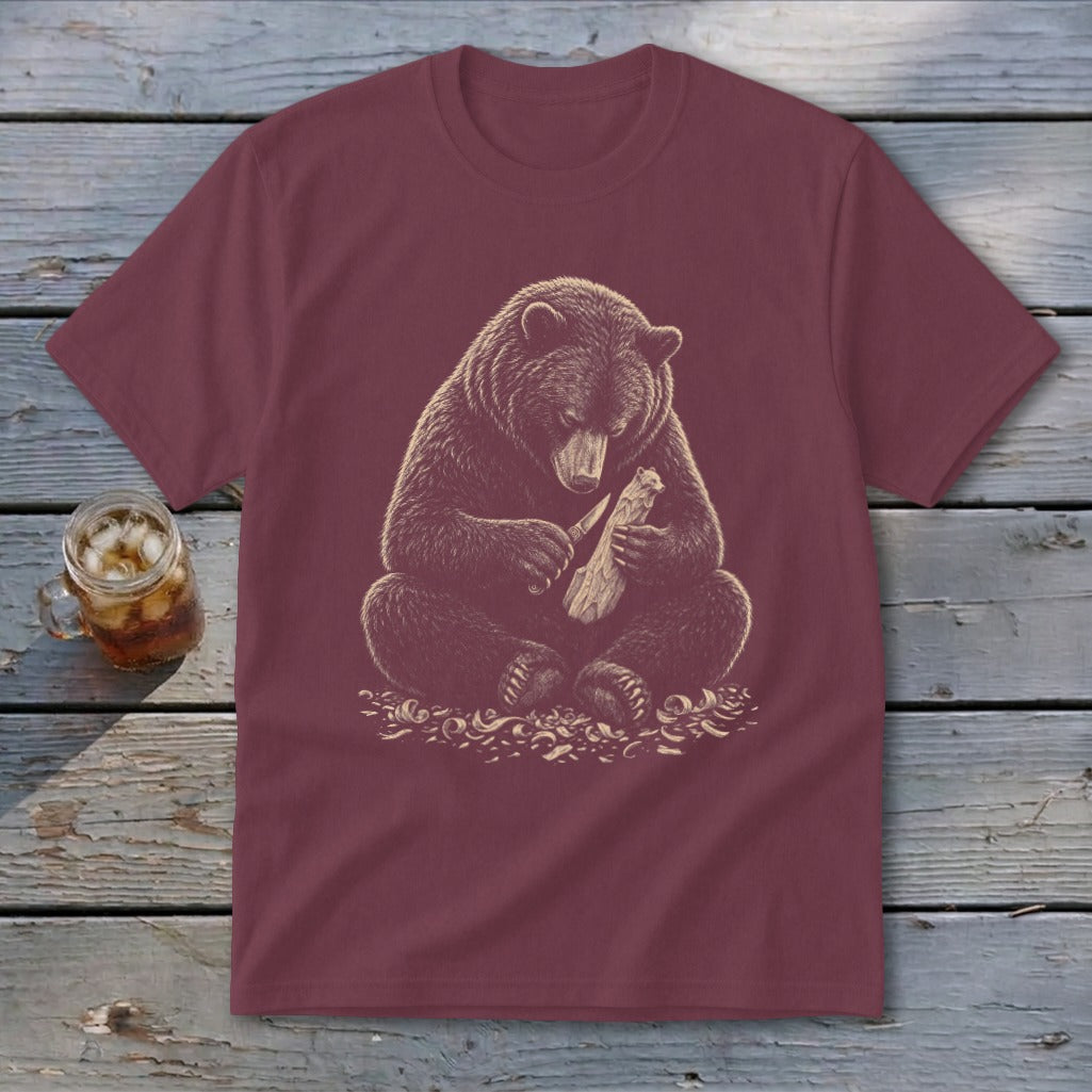 Maroon t-shirt with graphic of a bear carving wood with a knife.