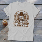 White t-shirt with brown lantern graphic and text "Established in the Hills".