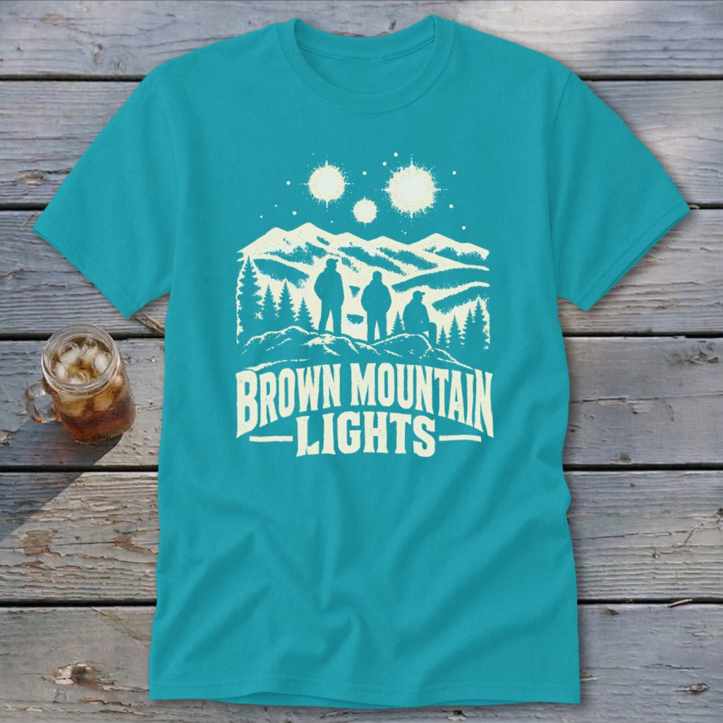 Turquoise t-shirt featuring a white graphic of three figures, mountains, glowing orbs, and text reading BROWN MOUNTAIN LIGHTS.