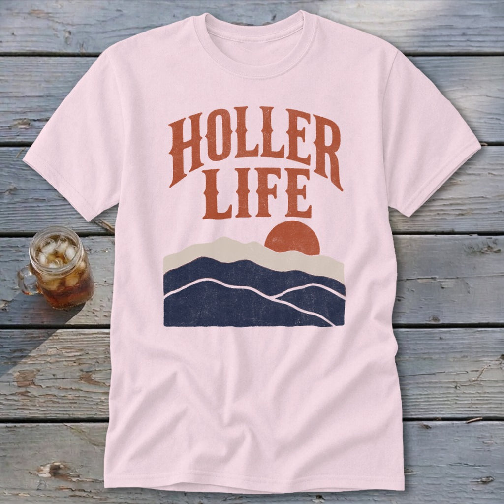 Light pink short-sleeve t-shirt with orange text reading "HOLLER LIFE" over a retro mountain landscape graphic.