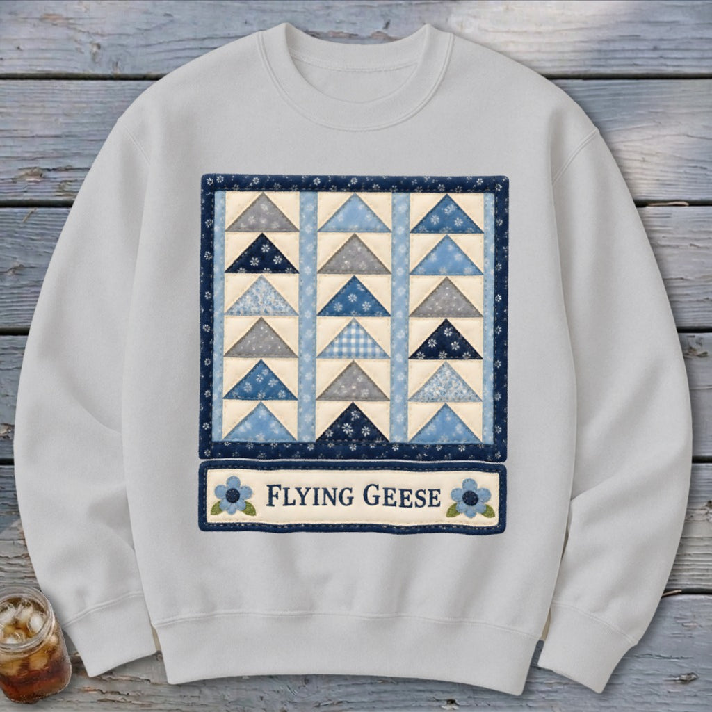 White sweatshirt with a blue and gray triangle quilt design and "Flying Geese" text.