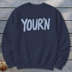 Navy sweatshirt with light blue "YOUR'N" text across the chest.
