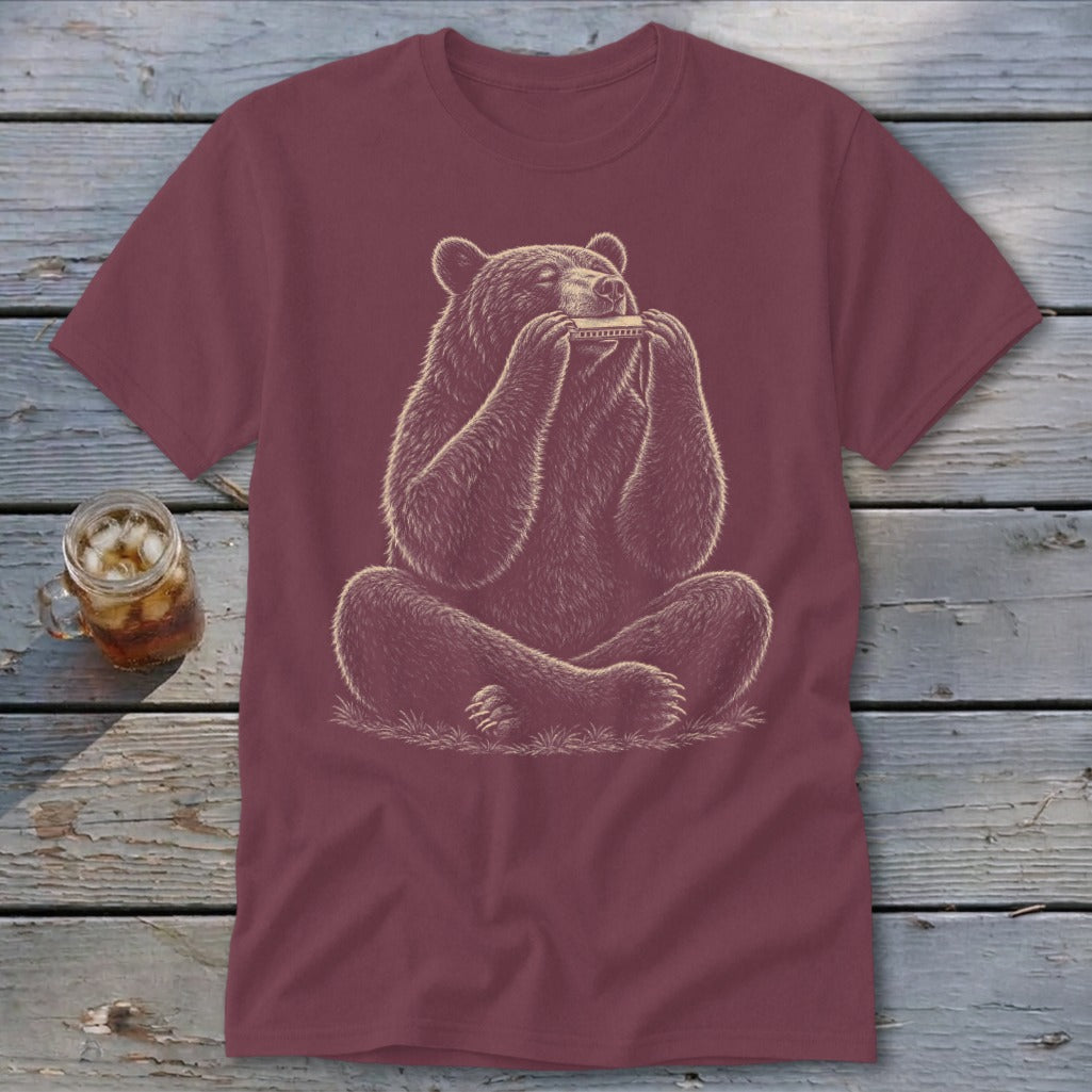 Bear sitting and playing a harmonica on a maroon t-shirt.